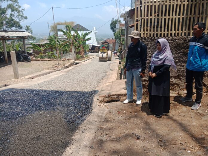 Kades Panembong Yanto Kriswanto memantau pengaspalan jalan
