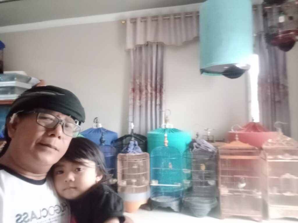 H. Ujang Selamet bersama cucunya melihat burung peliharaannya